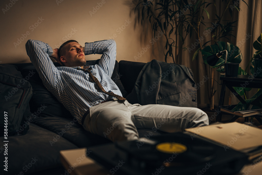 A man is listening to relaxing music on gramophone after a hard working day