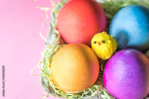 Overhead Angle of Colorful vibrant easter eggs and a yellow chick in a nest 