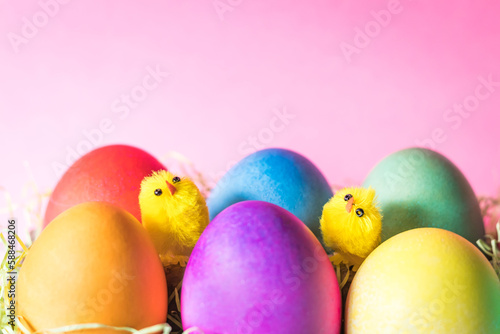 Colored easter eggs and chicks on a pink background