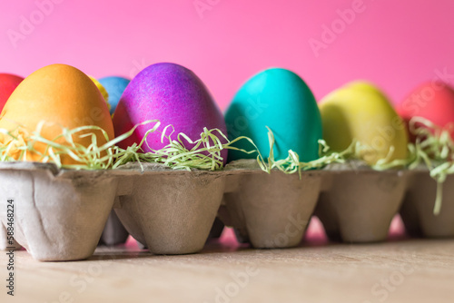 Colored easter eggs in a basket on a pink background
