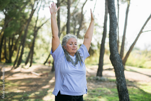 Mature old woman with dreadlocks practicing yoga and tai chi outdoors - wellbeing and wellness