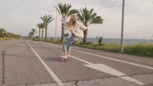 Cool skater woman skating on city street by the beach