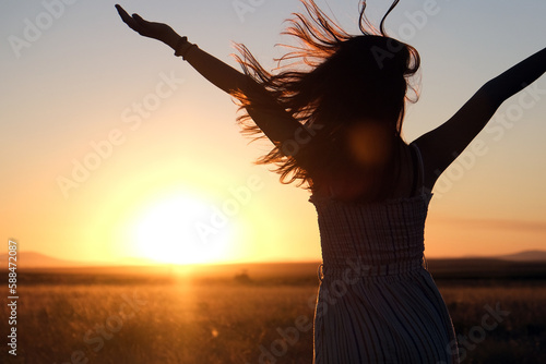 silhouette of a girl with her hair blowing in the wind at sunset