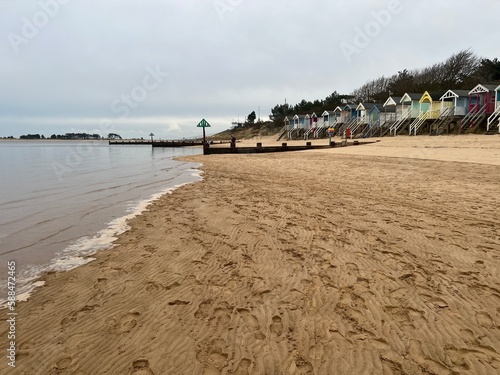 Landscape of bright painted beach huts on the beautiful sandy beach at Wells Next The Sea in Norfolk East Anglia uk with vast sands and ocean on dull early Summer day photo