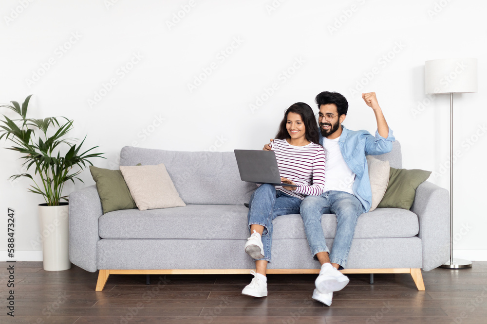Positive interracial young man and woman using computer at home Positive interracial young man and woman using computer at home