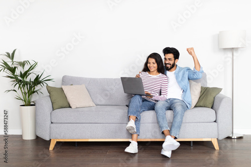 Positive interracial young man and woman using computer at home