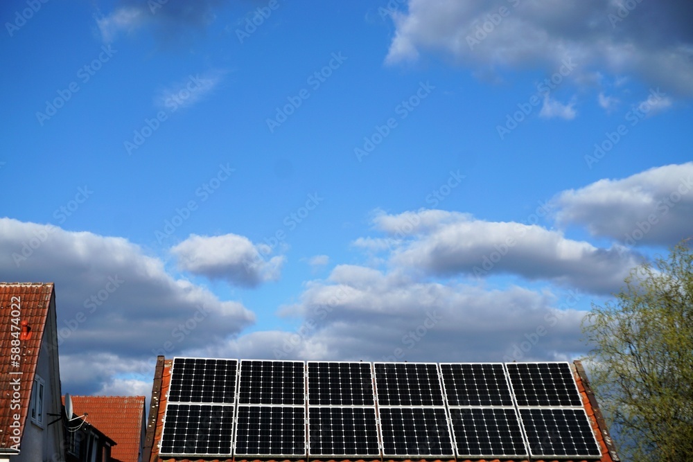 Solardach auf Gartenhäuschen vor Himmel mit weißgrauen Wolken bei Sonne am Abend im Frühling Solardach auf Gartenhäuschen vor Himmel mit weißgrauen Wolken bei Sonne am Abend im Frühling