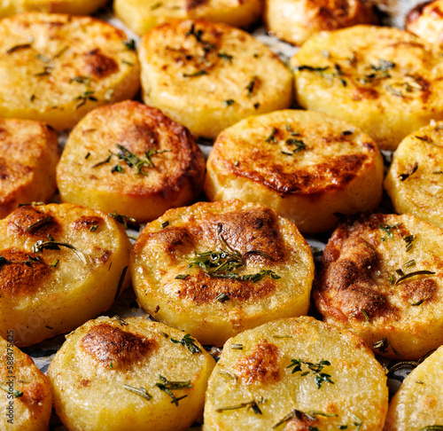 Roasted potato slices with aromatic herbs and spices, close up view