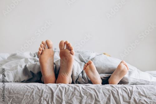father and son sleep in bed. focus on legs. Concept of friendly family