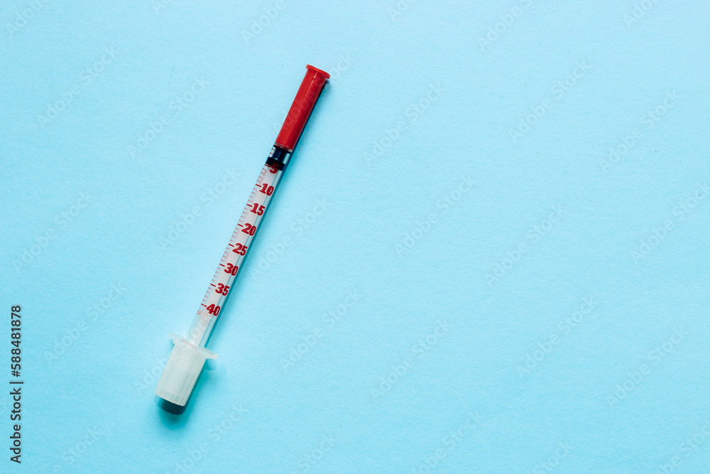 Thin insulin syringe on a blue background. Thin insulin syringe on a blue background.