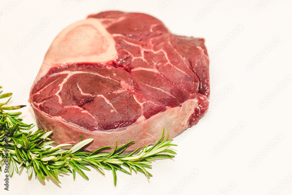 Fresh piece of meat large beef steak on the bone ossobuco with rosemary sprig.