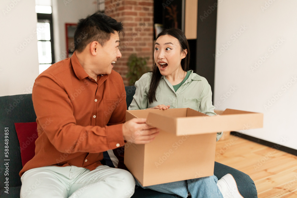 Emotional korean couple feel overjoyed unpacking cardboard parcel box with internet order enjoy unboxing shopping online Emotional korean couple feel overjoyed unpacking cardboard parcel box with internet order enjoy unboxing shopping online