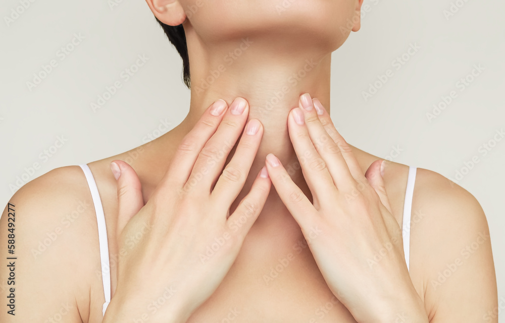 Fototapeta premium a woman holds her throat with her hand because of problems with her throat and thyroid gland