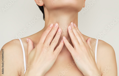 a woman holds her throat with her hand because of problems with her throat and thyroid gland photo