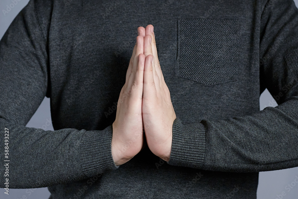 Hands in prayer gesture close-up, hands in gray sweater. Sign of entreaty, reconciliation.