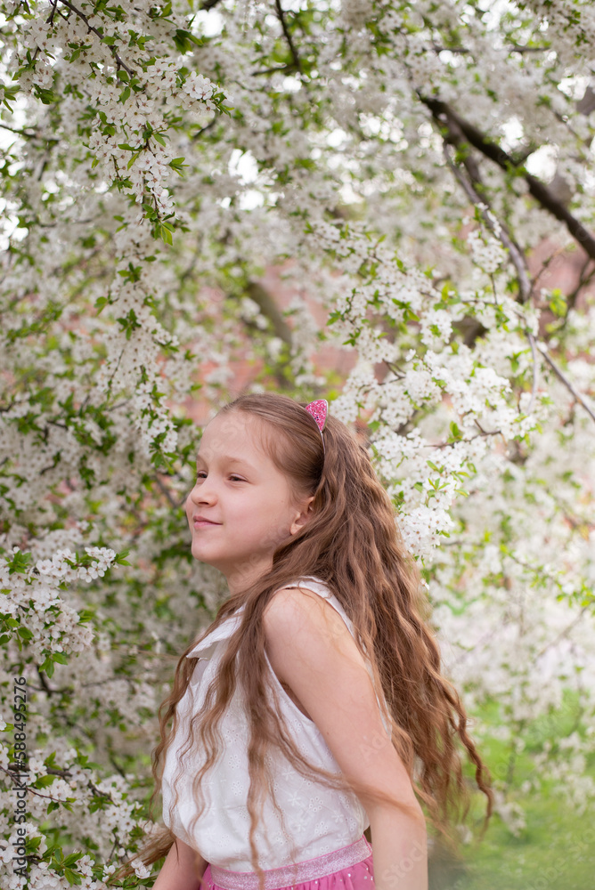 Adorable 9 years old girl with long curly hair surrounded by plenty branches blossoming of white spring flowers. Portrait of young girl Adorable 9 years old girl with long curly hair surrounded by plenty branches blossoming of white spring flowers. Portrait of young girl