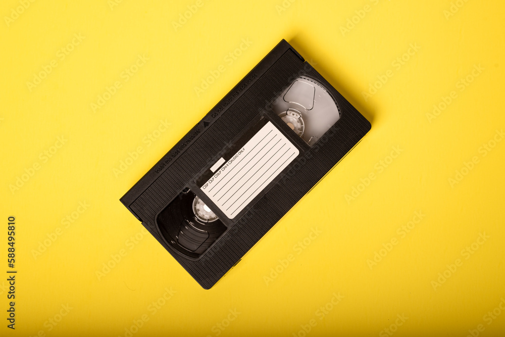 VHS Tape - Video Tape on Yellow Background. VHS Tape, a staple of an age before streaming, when movie rental stores were a necessary element of watching a movie at home. VHS Tape - Video Tape on Yellow Background. VHS Tape, a staple of an age before streaming, when movie rental stores were a necessary element of watching a movie at home.