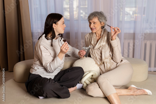An elderly woman in excellent shape offers a chocolate to her granddaughter or a young girl and they engage in a pleasant and smiling conversation. Sharing love and affection, Family relationships.