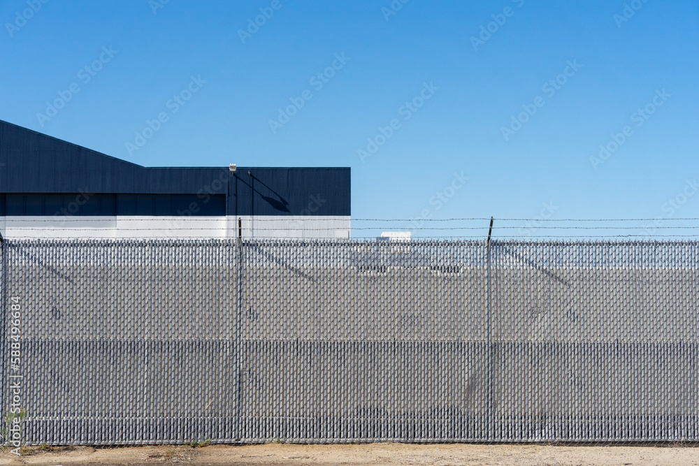 Chain link security fencing with vinyl slats and barbed wire topper in