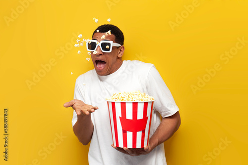 young frightened african american guy in 3d glasses with popcorn is watching horror movie