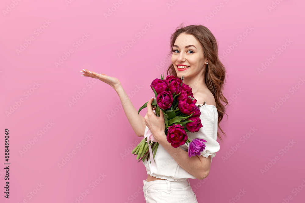 young beautiful girl holds bouquet of pink tulips and advertises copy space, woman in festive dress with flowers young beautiful girl holds bouquet of pink tulips and advertises copy space, woman in festive dress with flowers