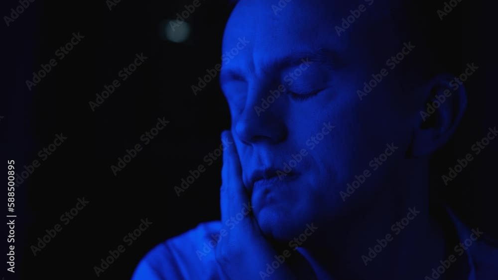 Sad tired man in the dark, close-up Sad tired man in the dark, close-up