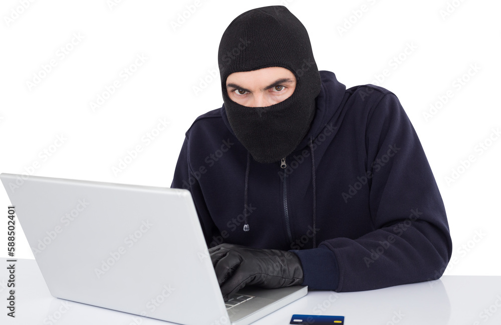 Hacker in balaclava hacking a laptop Hacker in balaclava hacking a laptop