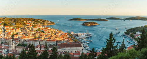 Panoramic skyline view of the old town of Hvar with turquoise water bay with yachts and islands in Dalmatia, Croatia