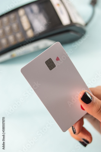 Hand with black painted nails holding a credit card on a dataphone