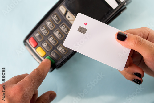 Hand with black painted nails holding a credit card on a dataphone photo