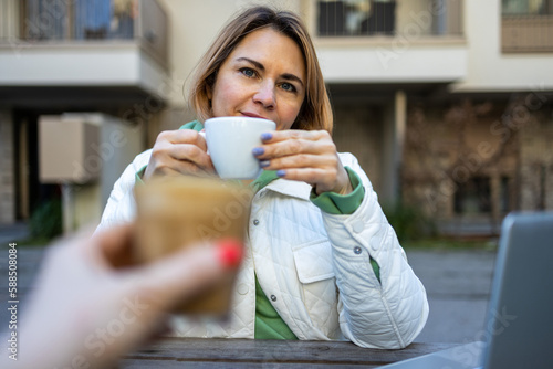 Middle aged matured smiling blond woman drinking a coffee in the street cafe