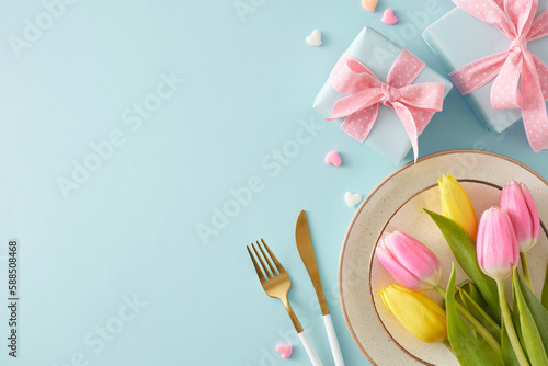 Women's Day concept. Top view photo of gift boxes with bows plate cutlery bouquet of flowers yellow pink tulips and colorful hearts on pastel blue background with empty space