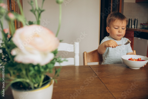 child eating oatmeal with strawberries at the table at home photo