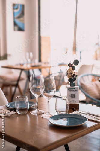 Mesa y sillas con platos, servilletas y vasos en un elegante restaurante costero.