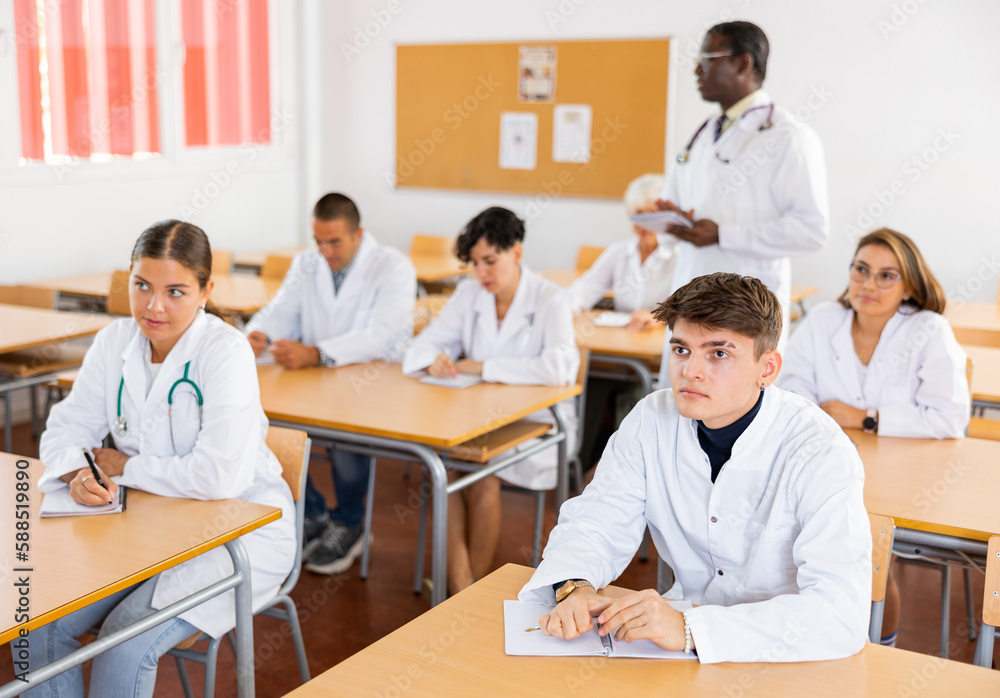Fototapeta premium Doctors different age sitting at desk in classroom working during lesson at adult education class