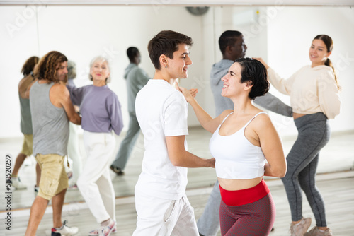 Dancing positive couples learning salsa in a dance school lesson