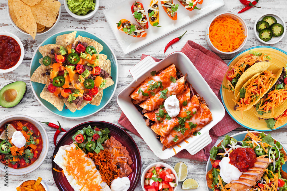 Mexican food table scene. Overhead view on a white wood background. Tacos, burrito plate, nachos, enchiladas, tortilla soup and salad. Mexican food table scene. Overhead view on a white wood background. Tacos, burrito plate, nachos, enchiladas, tortilla soup and salad.