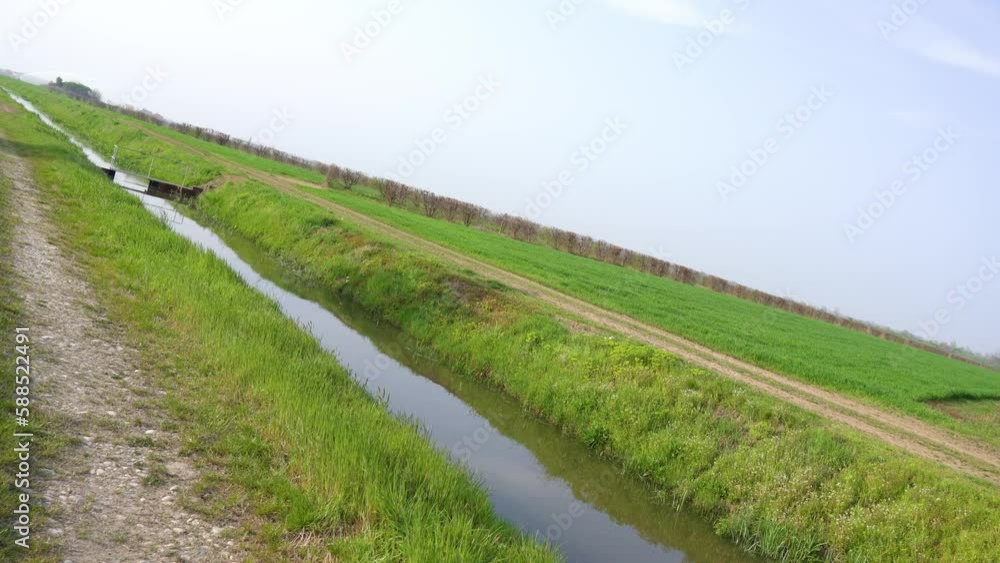 A channel of water in the middle of the grass of the fields A channel of water in the middle of the grass of the fields