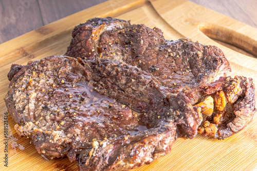 Roasted sirloin steak cut into steaks on a wooden board, on a wooden table.