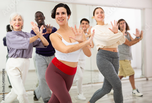 Group of active people engaged in a dance studio practicing energetic lindy hop movements in class