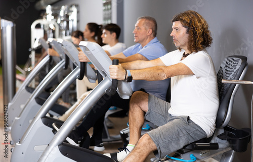Sports on cardio equipment by people of different ages in a modern gym