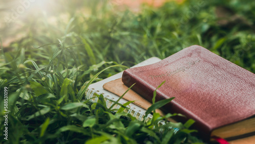 Bible laying on the meadow with notebook green background A solitary concept with a calm atmosphere. photo