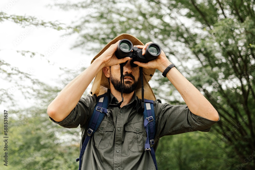 Hiker with backpack using binoculars in the wild. Field biologist or naturalist using binoculars to study wildlife or nature. Hiker with backpack using binoculars in the wild. Field biologist or naturalist using binoculars to study wildlife or nature.