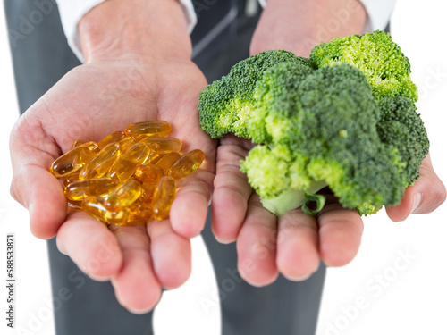 Businessman holding broccoli and vitamin pills