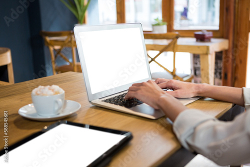 Cropped image of woman using laptop at table in careteria