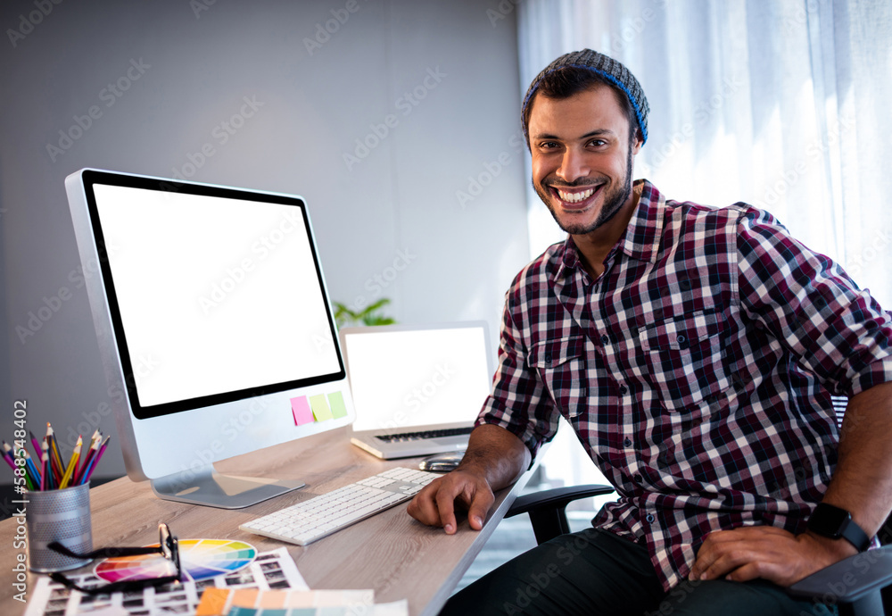 Businessman smiling while sitting on chair by computer Businessman smiling while sitting on chair by computer
