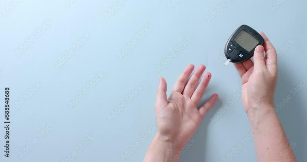 Hands of caucasian woman checking blood sugar level using glucometer, copy space, slow motion Hands of caucasian woman checking blood sugar level using glucometer, copy space, slow motion
