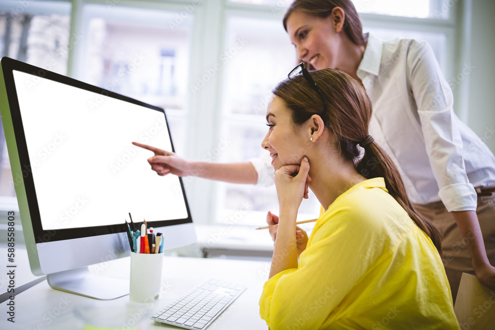 Women discussing over computer monitor Women discussing over computer monitor