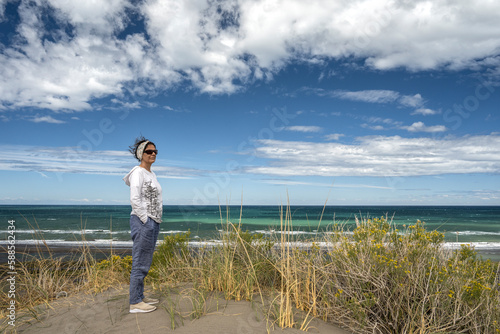 Senior woman standing in front of the ocean on a sunny day, in Bahia Creek, Chubut, Argentina. photo