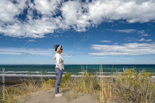 Senior woman standing in front of the ocean on a sunny day, in Bahia Creek, Chubut, Argentina. photo